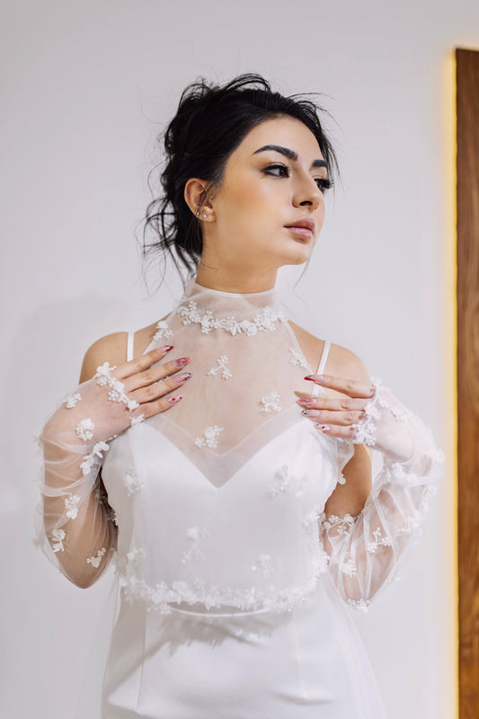 A bride with natural wedding makeup is trying on the dress in front of the mirror
