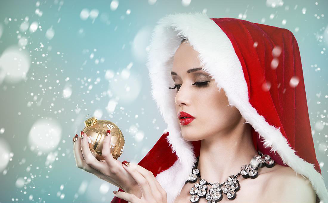 A woman with makeup is wearing a Christmas cloak and holding a Christmas ball