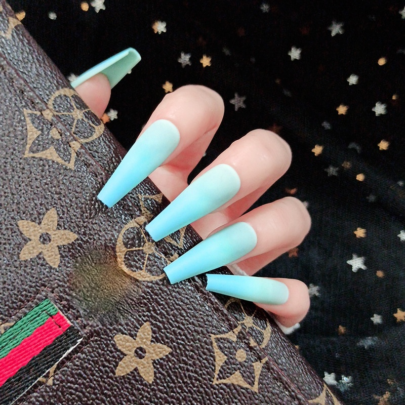 fingers wearing blue ombre nails is touching a clutch
